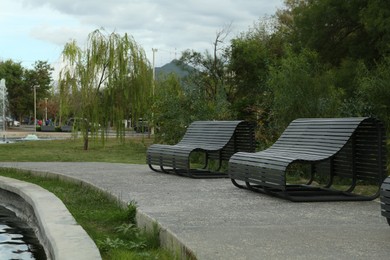 Photo of Beautiful view of black wooden benches and plants in park