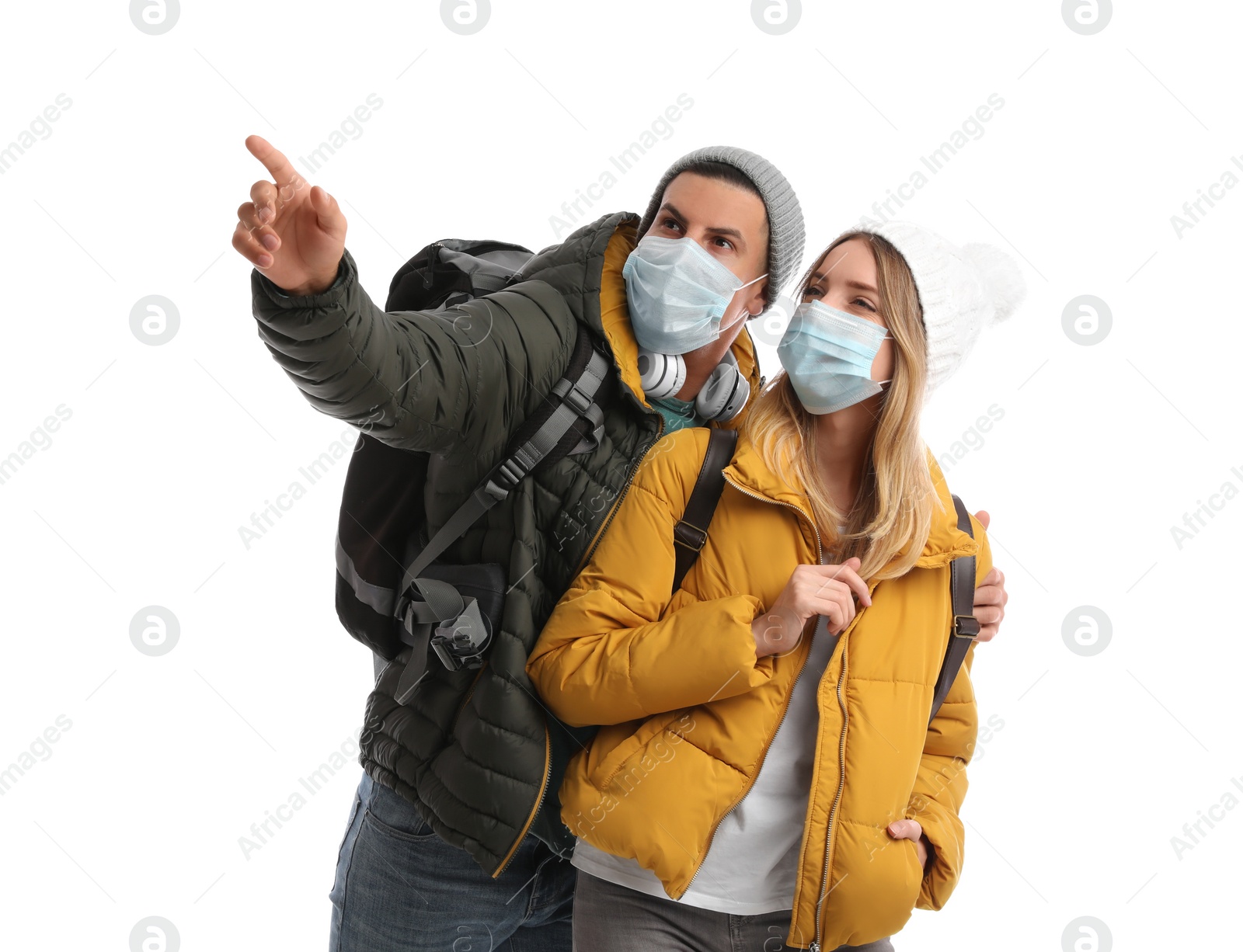 Photo of Couple in face masks and warm clothes on white background. Winter travel