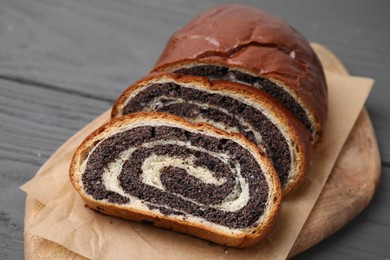 Photo of Cut poppy seed roll on grey wooden table, closeup. Tasty cake