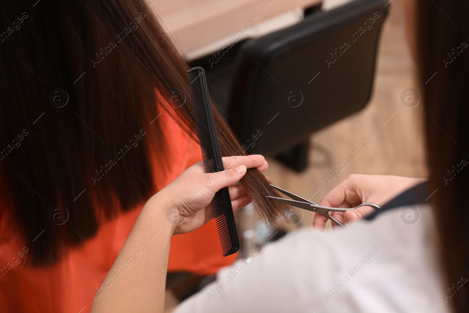 Photo of Stylist cutting hair of client in professional salon, closeup