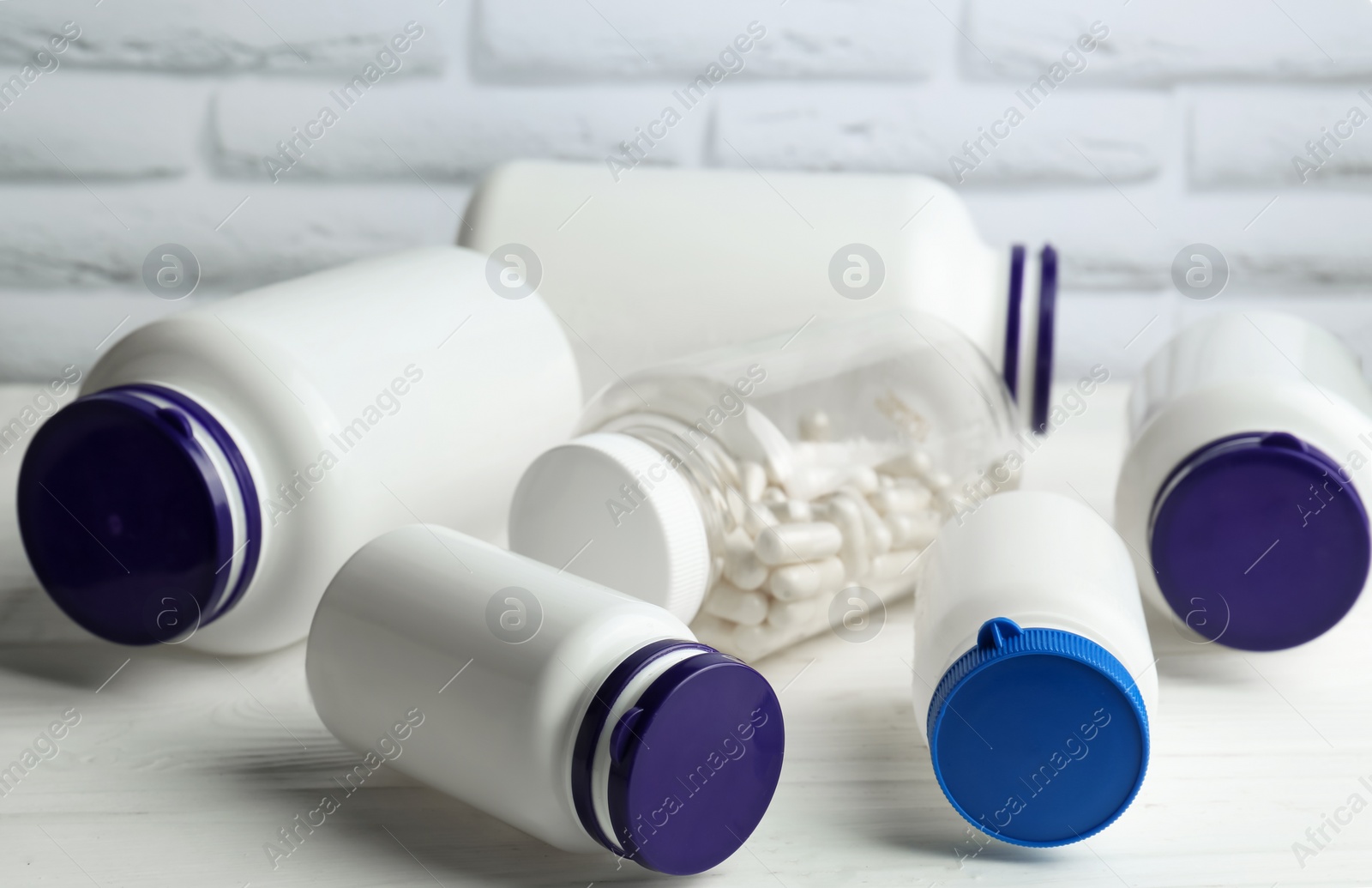 Photo of Medical bottles with pills on white wooden table, closeup