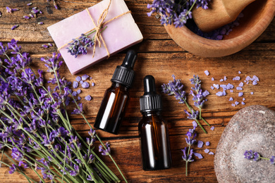 Photo of Cosmetic products and lavender flowers on wooden table, flat lay