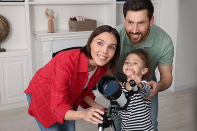 Happy family using telescope to look at stars in room