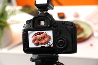 Photo of Professional camera with picture of meat medallion on display in photo studio, closeup. Food stylist