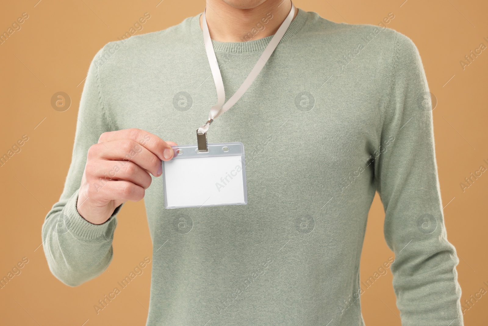 Photo of Man with blank badge on light brown background, closeup