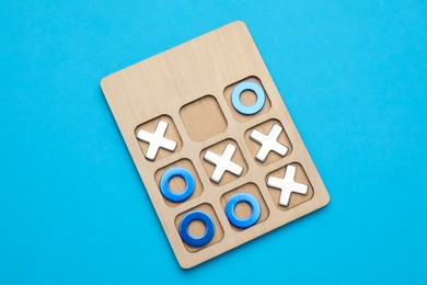 Tic tac toe set on light blue background, top view