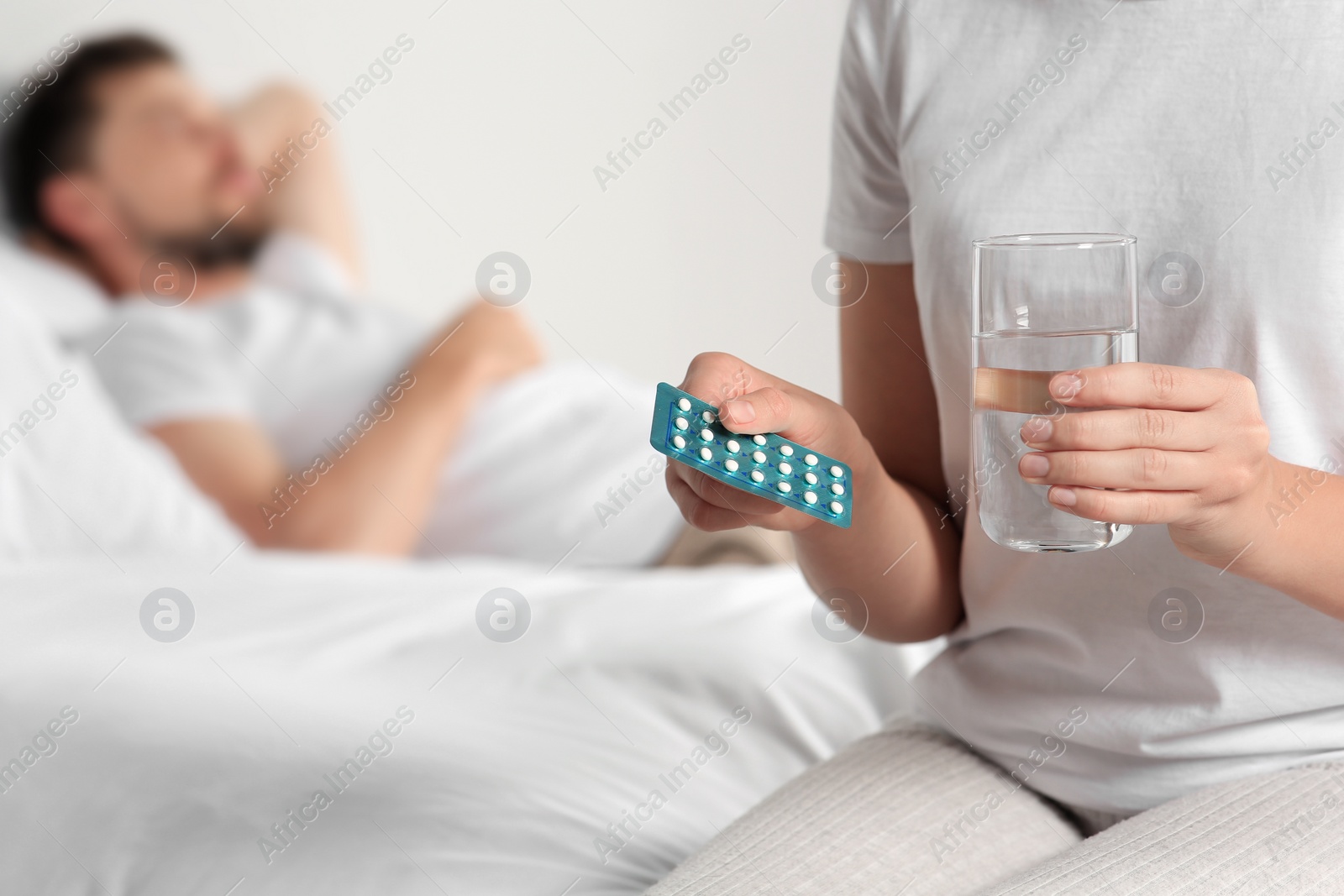 Photo of Couple in bedroom. Woman taking oral contraception pill, closeup