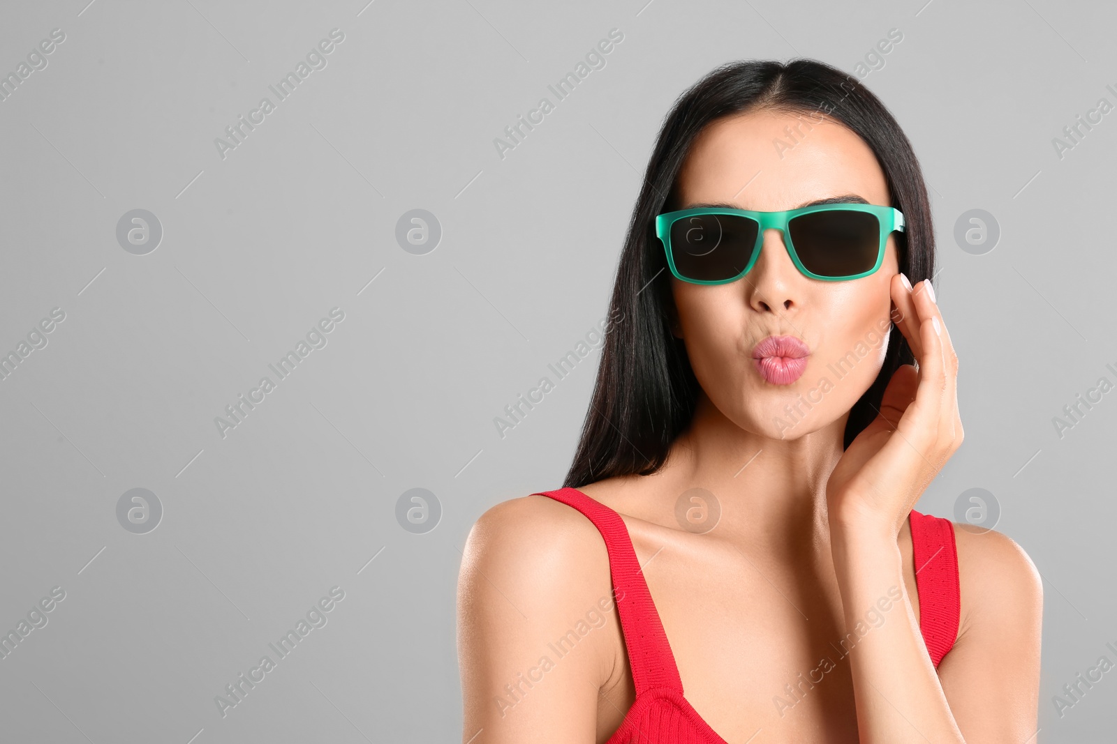 Photo of Beautiful woman wearing sunglasses on grey background. Space for text