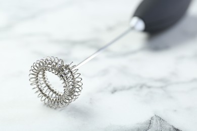 Photo of Black milk frother wand on white marble table, closeup