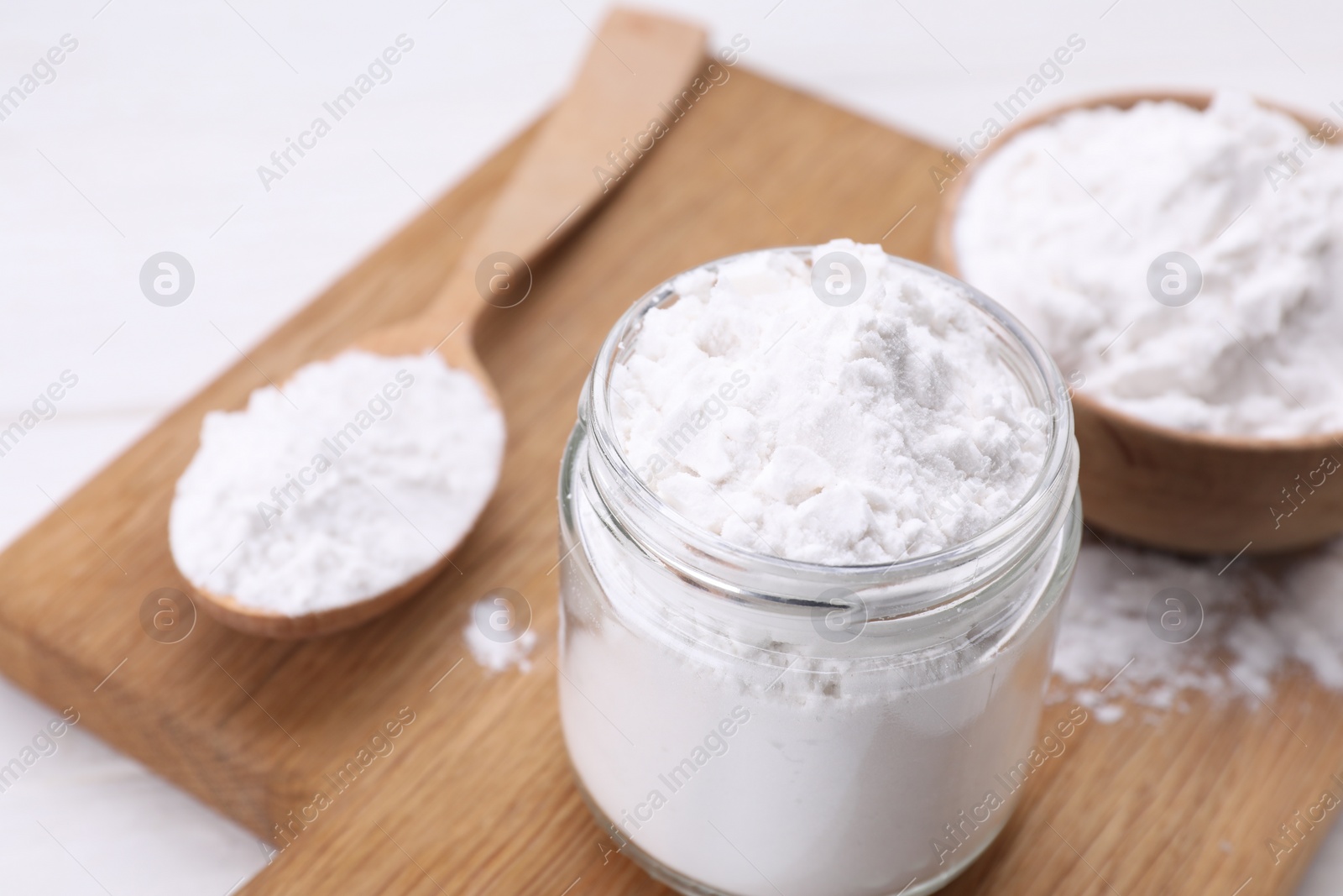 Photo of Jar and spoon of starch on wooden board, closeup