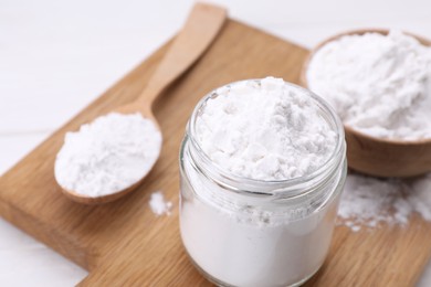 Photo of Jar and spoon of starch on wooden board, closeup