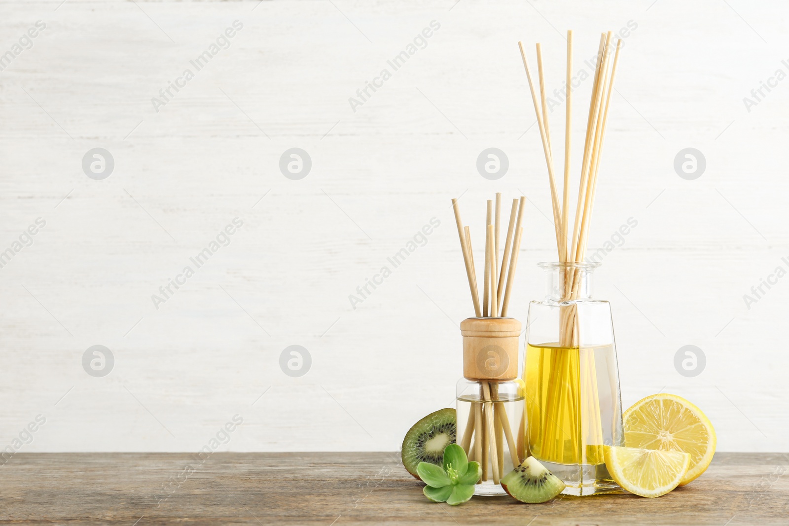 Photo of Composition with aromatic reed fresheners on wooden table against light background. Space for text
