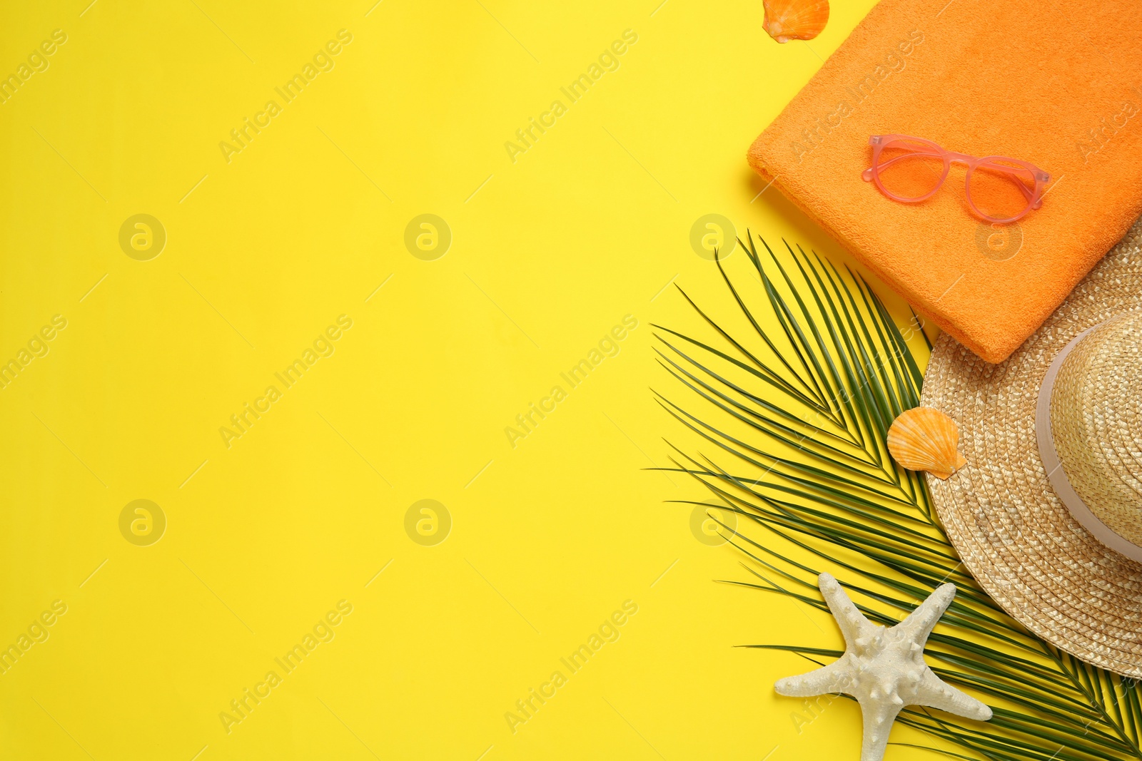 Photo of Beach towel, straw hat and sunglasses on yellow background, flat lay. Space for text