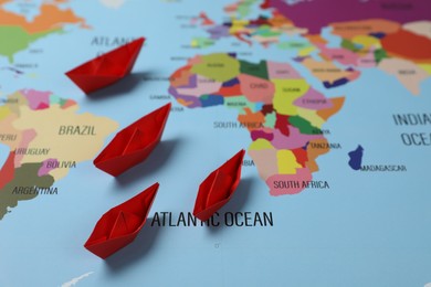 Red paper boats on world map. Space for text