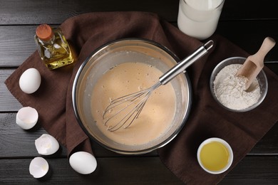 Flat lay composition with whisk and dough in bowl on wooden table