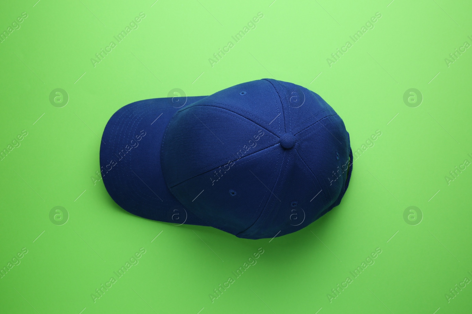 Photo of Stylish blue baseball cap on light green background, top view