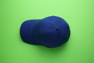 Stylish blue baseball cap on light green background, top view