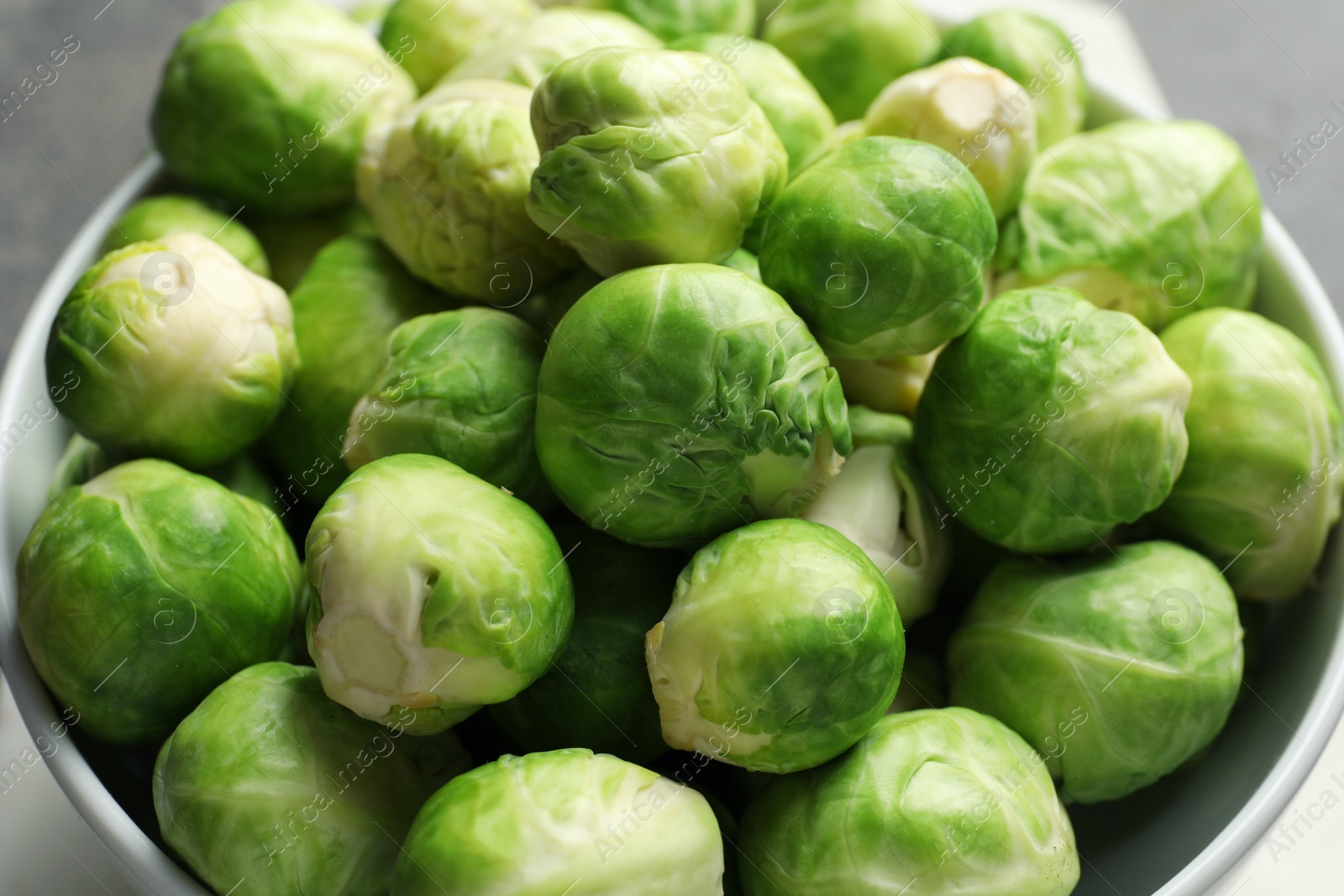 Photo of Fresh Brussels sprouts in bowl on table, closeup