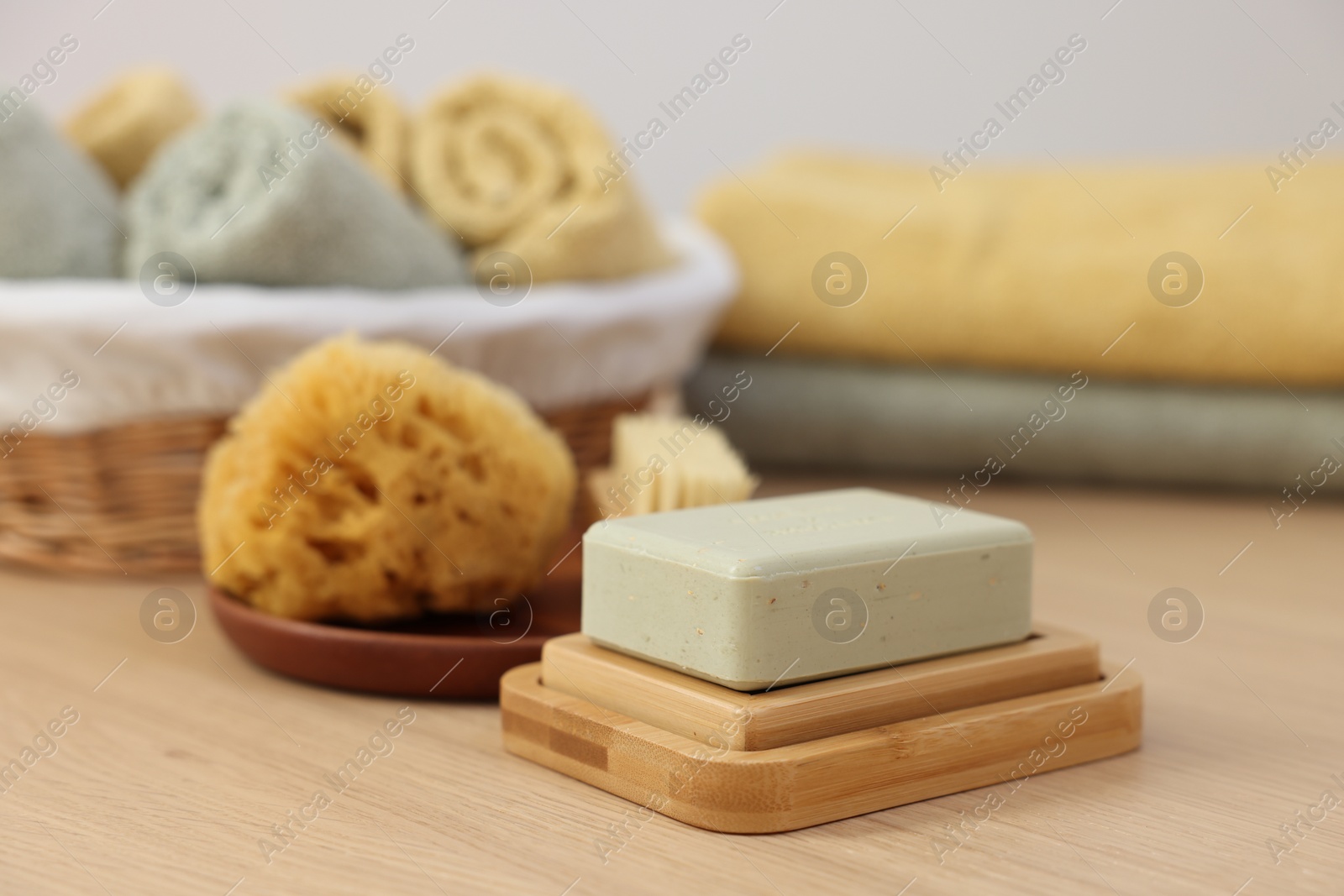 Photo of Soap bar and sponge on light wooden table. Spa therapy