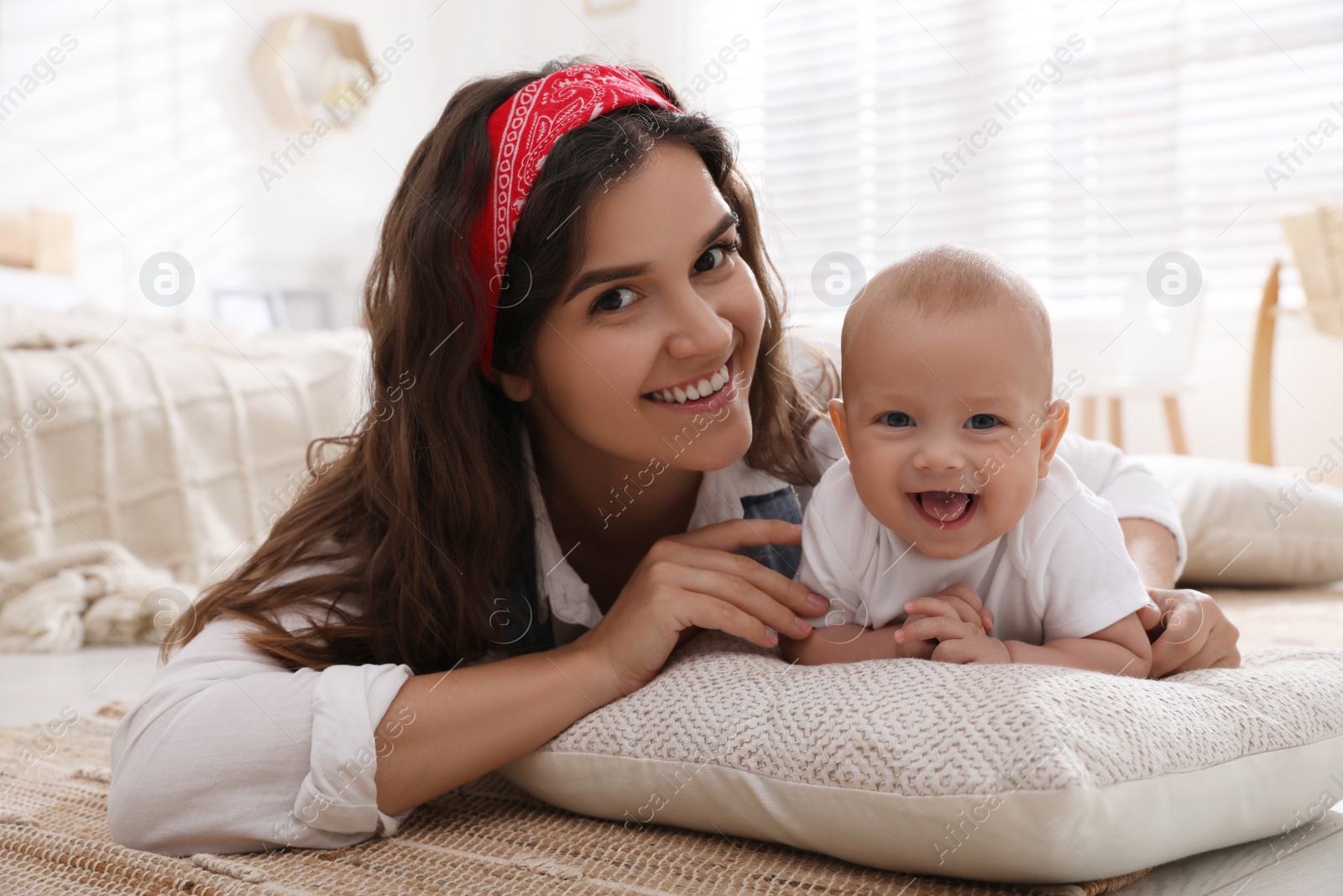 Photo of Happy young mother with her cute baby on floor at home