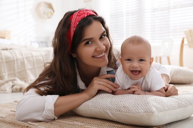 Happy young mother with her cute baby on floor at home