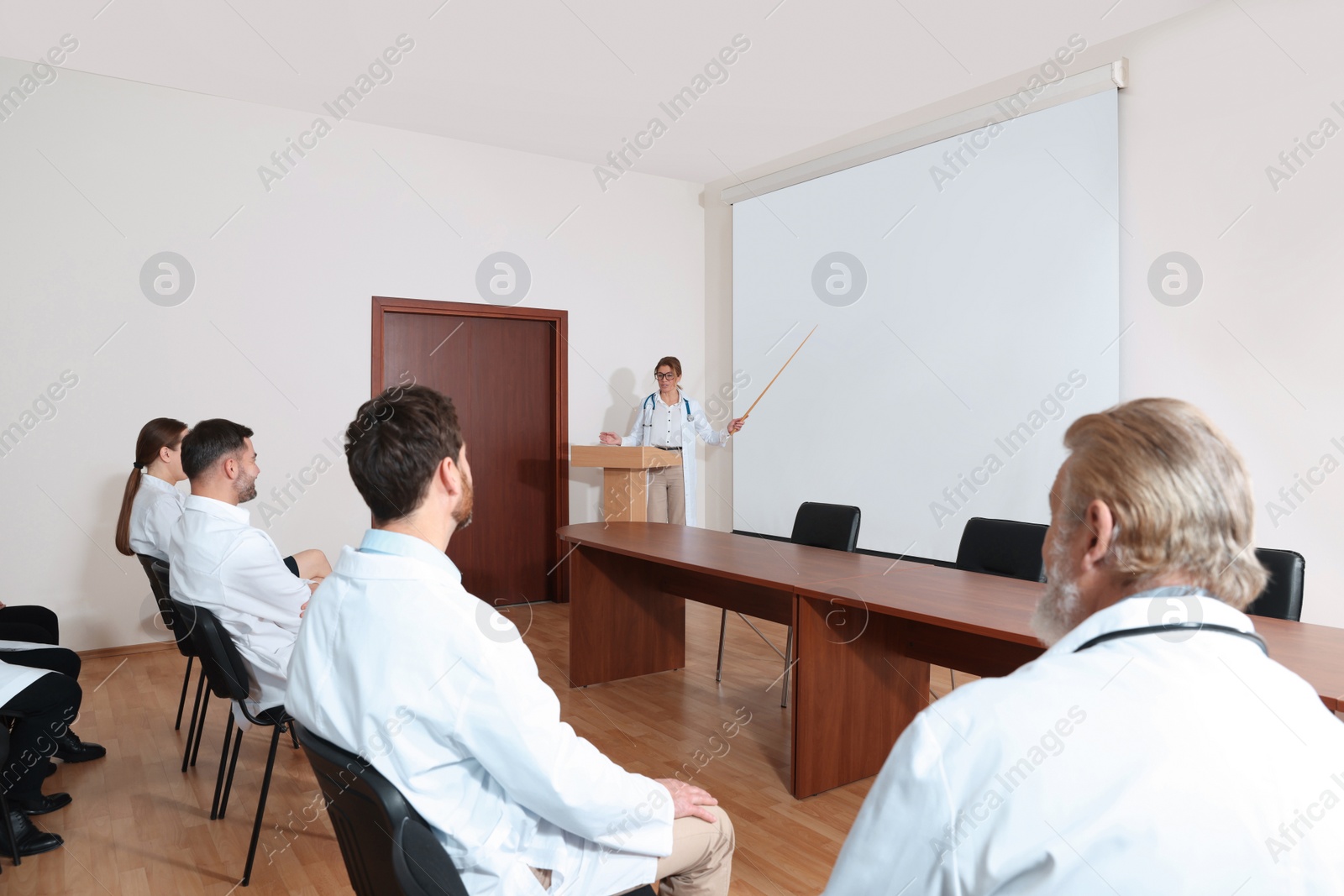 Photo of Doctor giving lecture in conference room with projection screen