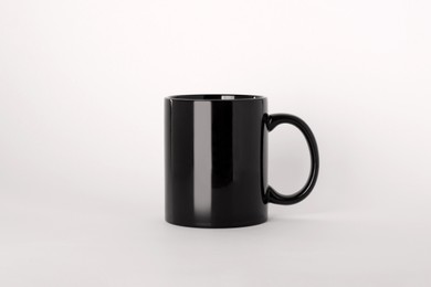 Photo of Blank black ceramic mug on light background