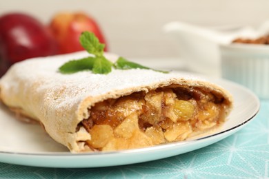 Photo of Delicious strudel with apples, nuts and raisins on table, closeup