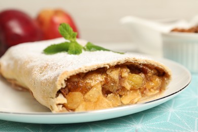 Delicious strudel with apples, nuts and raisins on table, closeup