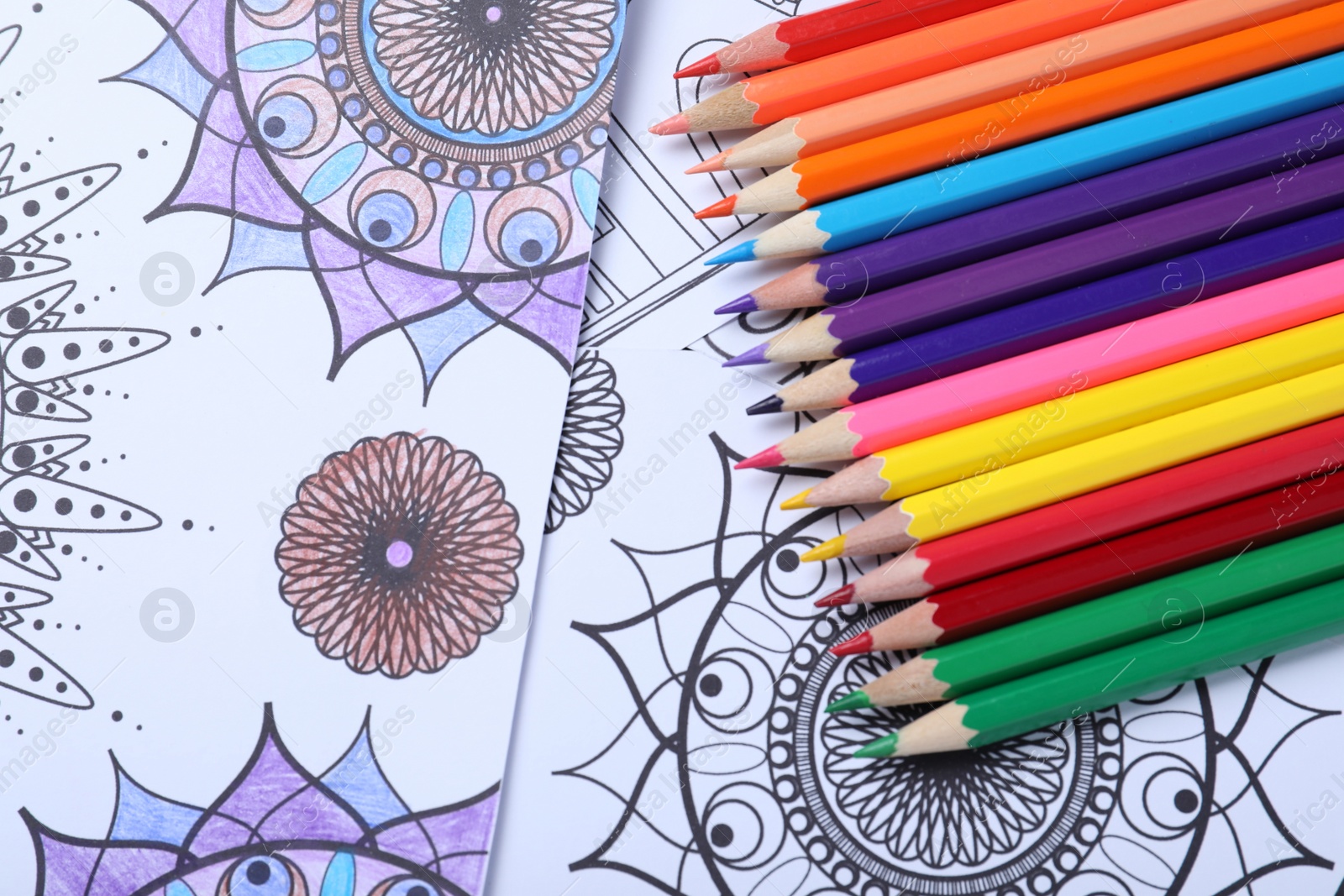 Photo of Pencils on antistress coloring pages, top view