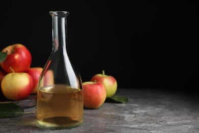 Photo of Natural apple vinegar and fresh fruits on grey table. Space for text