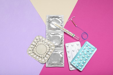 Photo of Contraceptive pills, condoms, intrauterine device and thermometer on color background, flat lay. Choice of birth control method