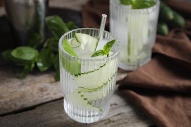 Photo of Refreshing cucumber water with basil on wooden table