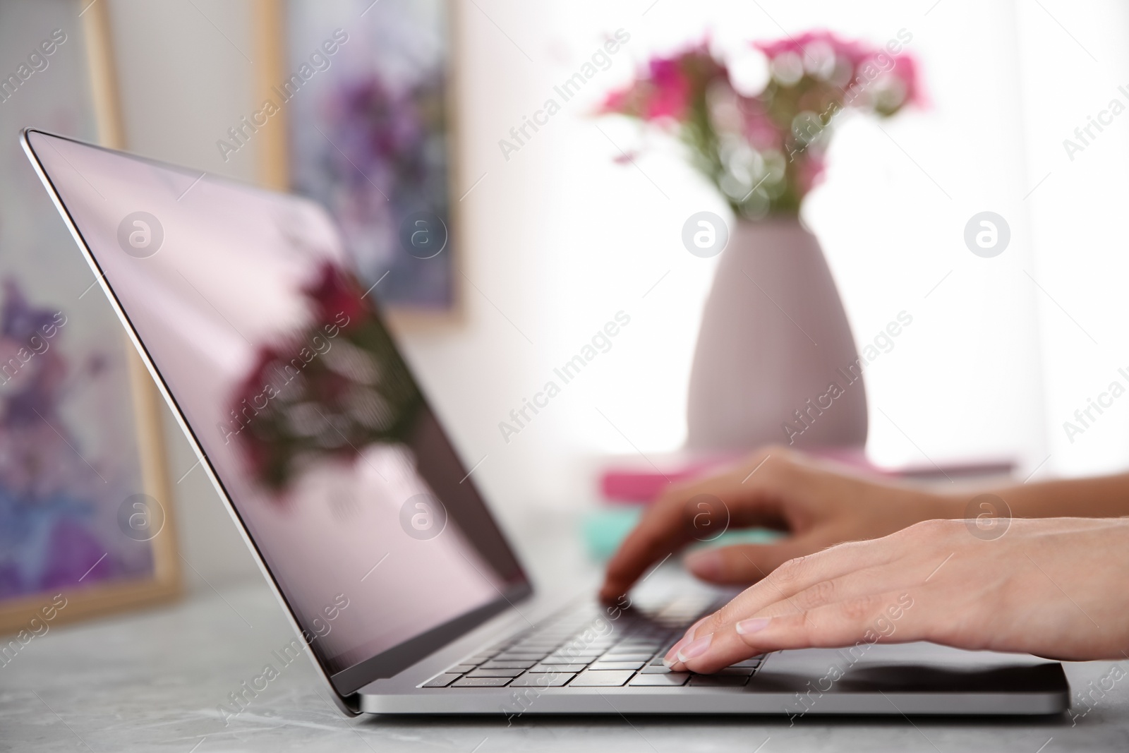 Photo of Woman working with modern laptop at light table, closeup