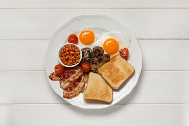Photo of Plate with fried eggs, mushrooms, beans, bacon, tomatoes and toasts on white wooden table, top view. Traditional English breakfast