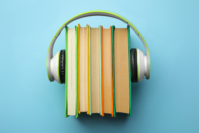 Photo of Books and modern headphones on light blue background, top view
