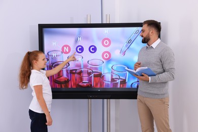 Teacher and pupil using interactive board in classroom during lesson