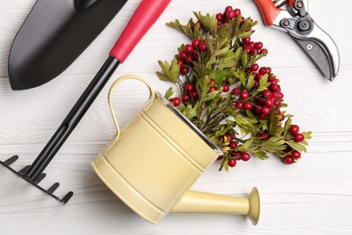 Flat lay composition with watering can and gardening tools on white wooden table