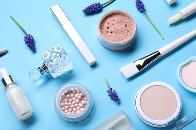 Composition with different makeup products and beautiful spring flowers on light blue background