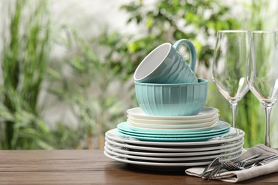 Photo of Beautiful ceramic dishware, glasses, cutlery and cup on wooden table outdoors, space for text