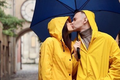 Photo of Lovely young couple with umbrella kissing under rain on city street