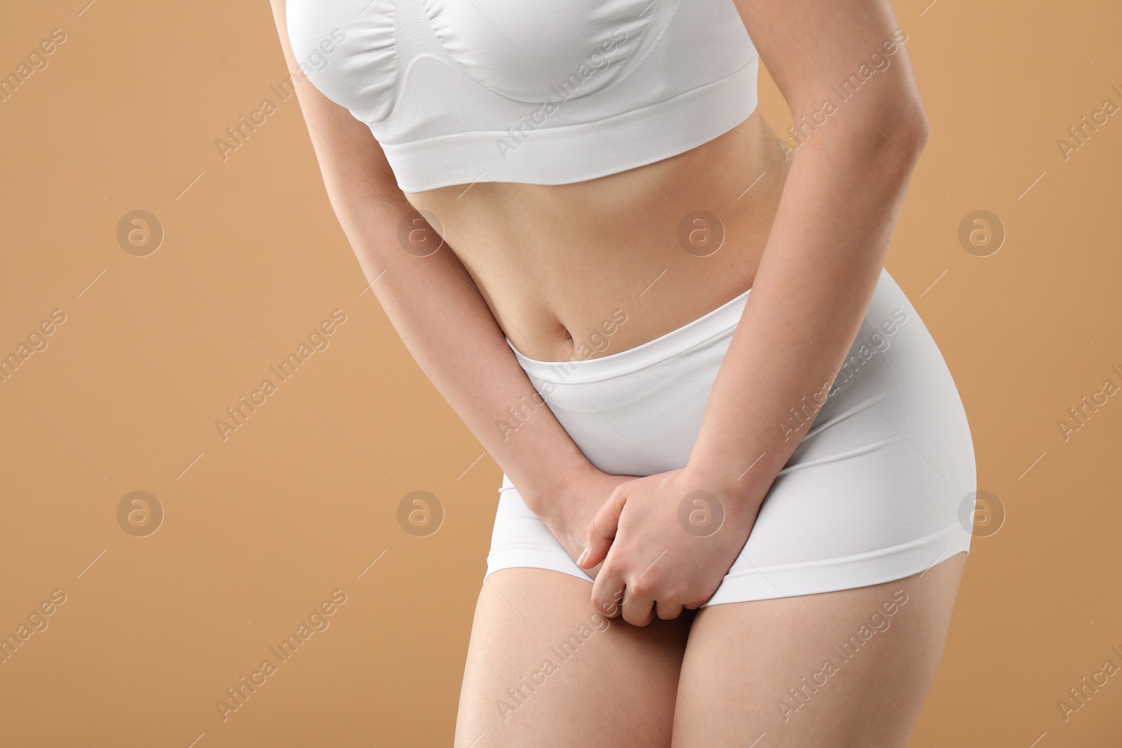 Photo of Woman suffering from cystitis on beige background, closeup. Space for text