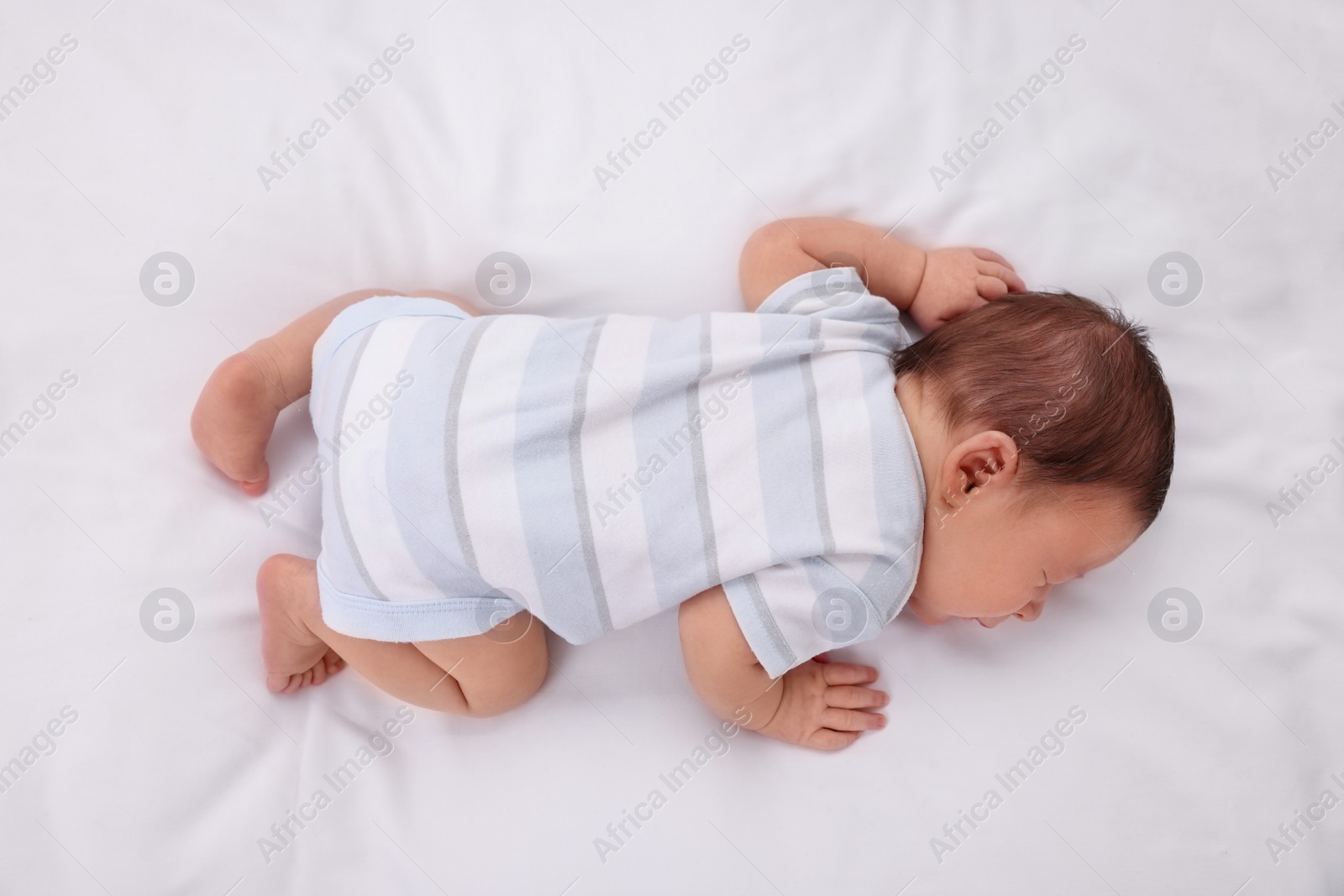 Photo of Cute newborn baby sleeping in crib, top view. Bedtime