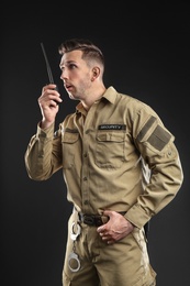 Photo of Male security guard using portable radio transmitter on dark background