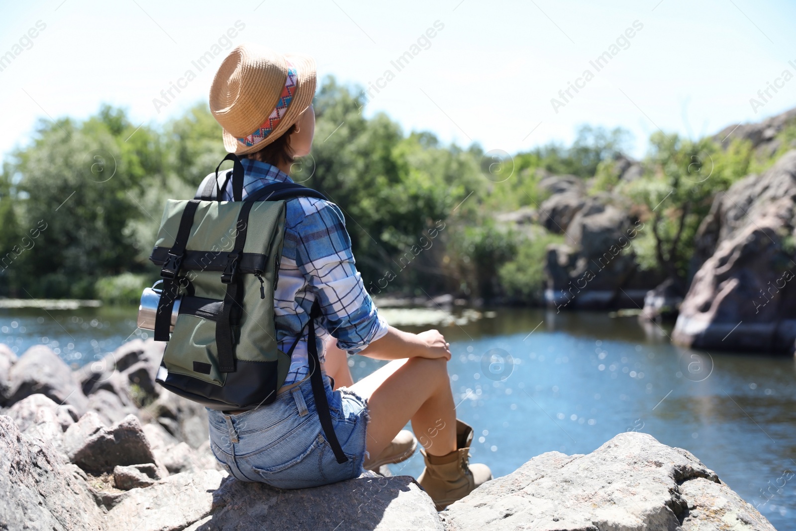 Photo of Young woman on rock near river. Summer camp