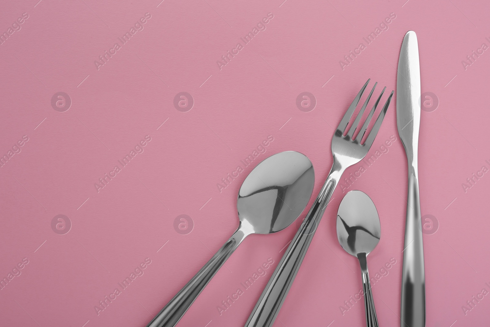 Photo of Stylish cutlery set on pink background, flat lay. Space for text