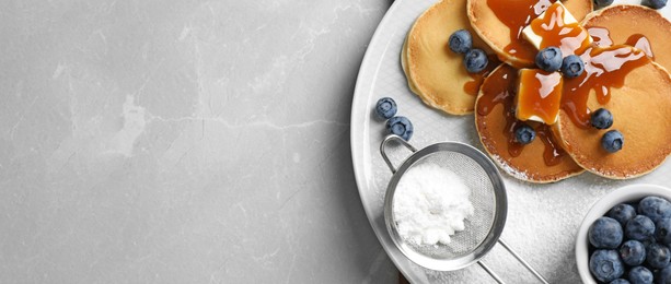 Tasty pancakes with blueberries served on grey marble table, flat lay with space for text. Banner design