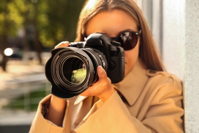 Private detective with camera spying near building on city street