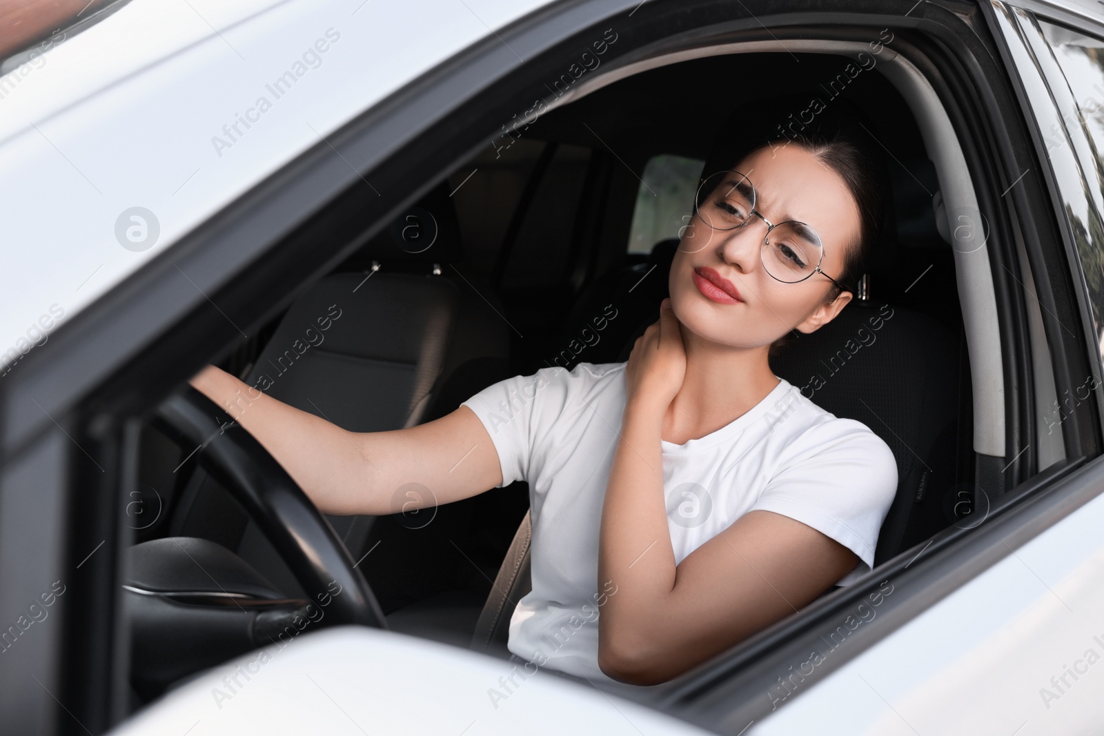 Photo of Young woman suffering from neck pain in her car