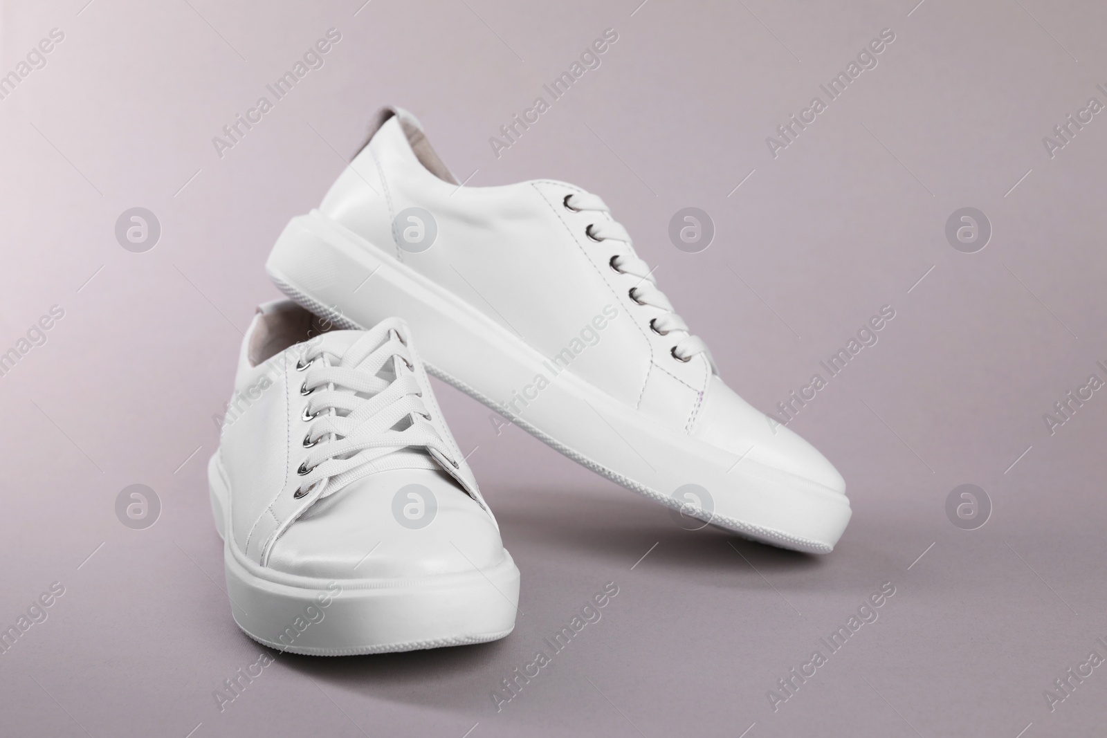 Photo of Pair of stylish white sneakers on grey background